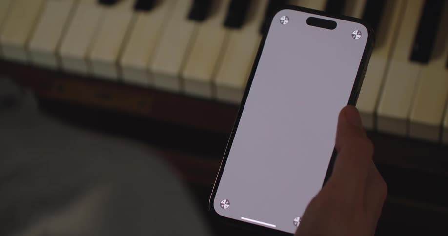 A man scrolls through his phone while sitting at a piano