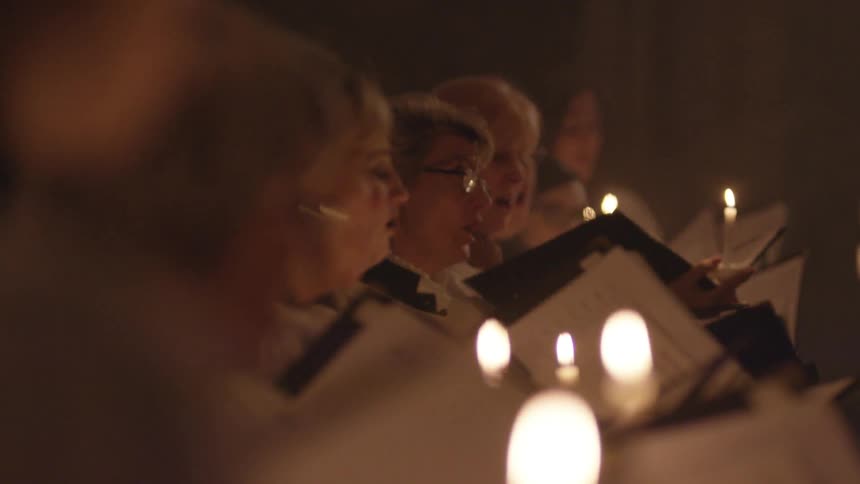A choir sings by candlelight
