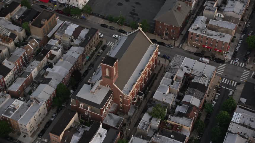 Aerial footage of Saint Paul Church in South Philadelphia seen during sunset over an urban residential neighborhood