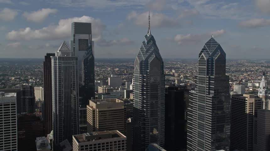 Fly over Downtown Philadelphias tallest towers during daylight showing the reflection of modern buildings in mirrored skyscrapers