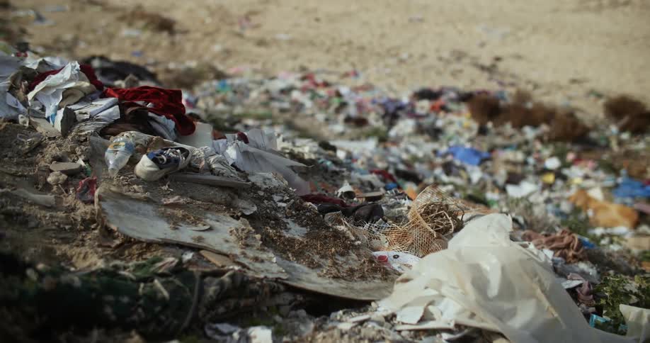 Garbage strewn along a sandy slope on a windy day