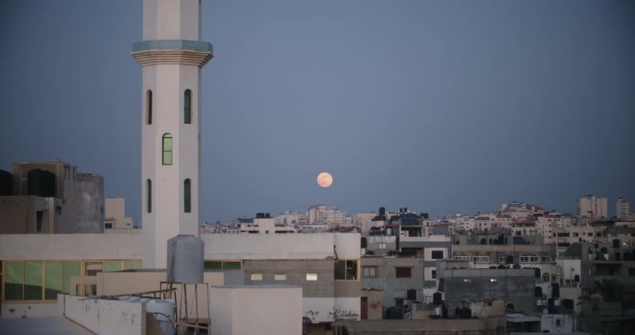 A full moon rises over a neighborhood