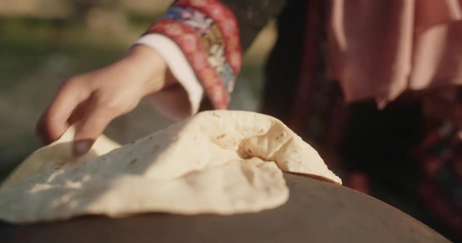 Woman bakes flatbread flipping it over