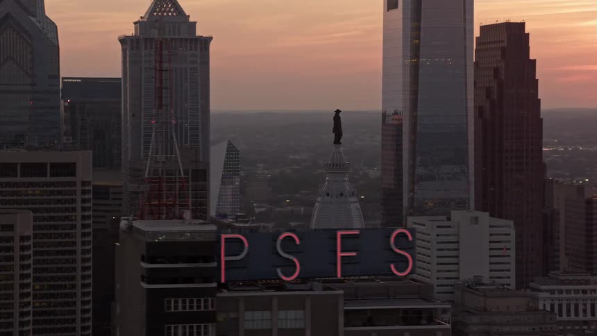 Aerial stock footage of William Penn statue on Philadelphia City Hall at dusk with the sun setting in the background