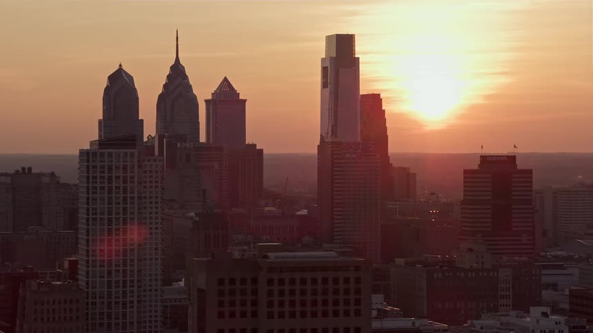 A breathtaking aerial view of the setting sun diffused by fog shining on the Downtown Philadelphia skyline during dusk