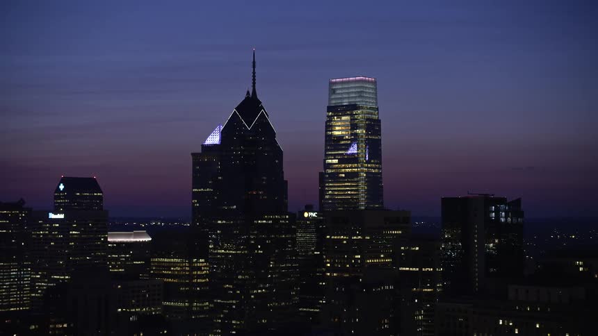 An aerial video of Philadelphias high rises including One and Two Liberty Place and Comcast Center at night under a purple sky