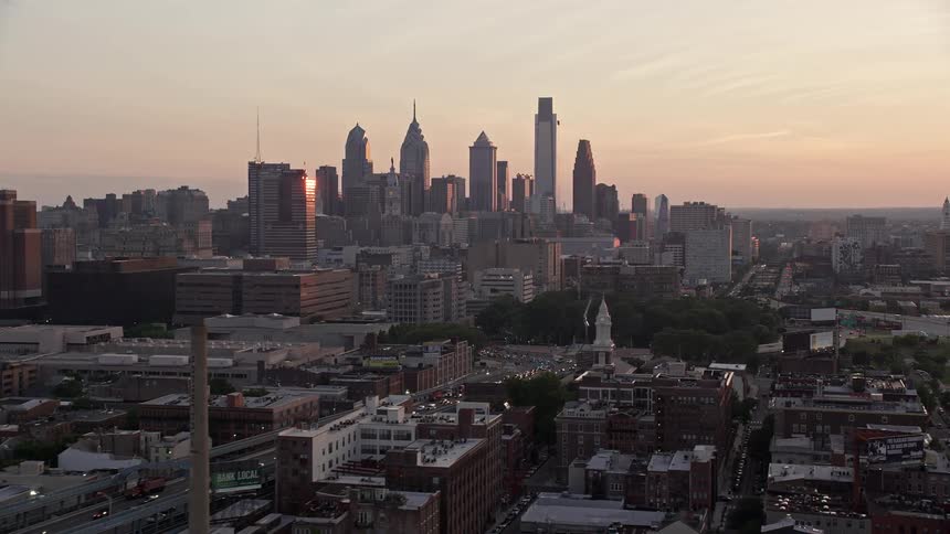 A stunning aerial view of the Benjamin Franklin Bridge and the Philadelphia skyline at dusk with the sun setting over the Delaware River