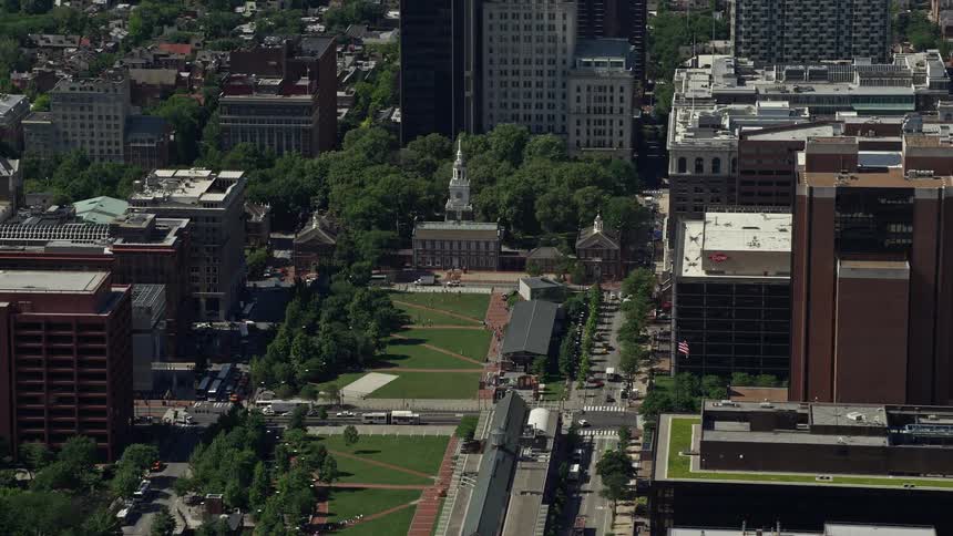 Aerial footage of Independence Hall at Independence Mall in Philadelphia during a sunny day showcasing the historical landmark and downtown area