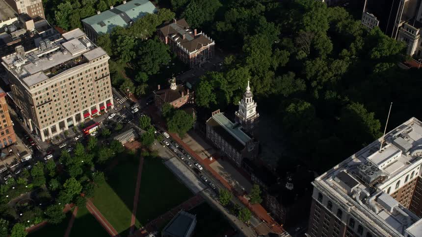Aerial footage of Independence Hall and park in Downtown Philadelphia Pennsylvania approaching and orbiting the historic landmark in partly cloudy skies during midday