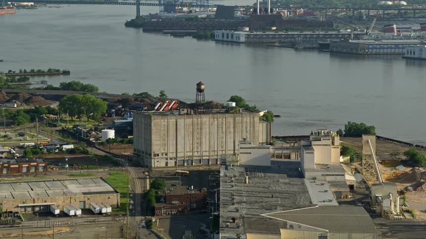 An aerial view of manufacturing plants and warehouses situated near the Delaware River in Camden New Jersey captured during the daytime in partly cloudy skies