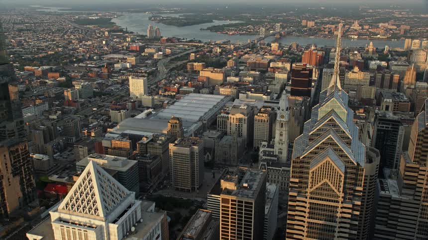 Aerial footage showcasing Downtown Philadelphia skyscrapers landmarking the Convention Center and City Hall as the camera approaches capturing the beautiful sunset