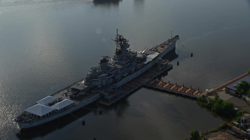 Approaching and flying over USS New Jersey on Delaware River Camden New Jersey amidst partly cloudy skies