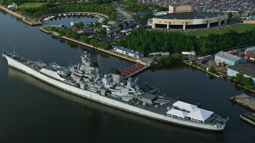 Aerial footage captures the approach of USS New Jersey on Delaware River showcasing BB&T Pavilion Balzano Marine Terminal and Philadelphias industrial landscape