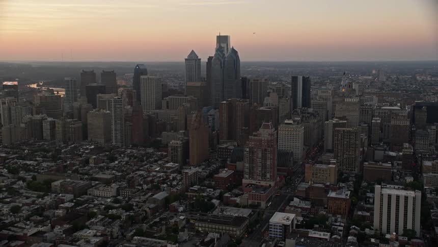 Aerial footage of Downtown Philadelphia skyscrapers at sunset with a reverse view