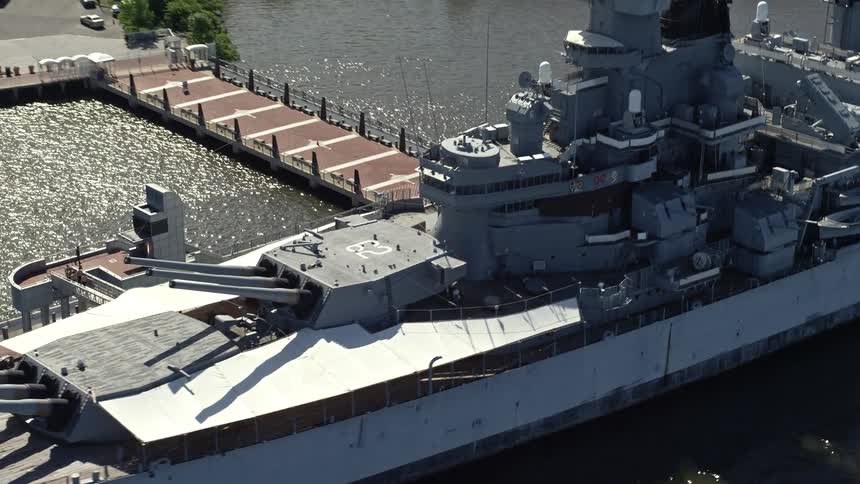 Aerial footage of the battleship USS New Jersey cruising on a sunny day along the coast of Camden New Jersey