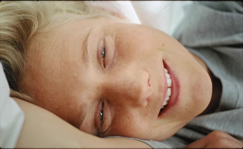 A young woman is laying down on her bed in the day time