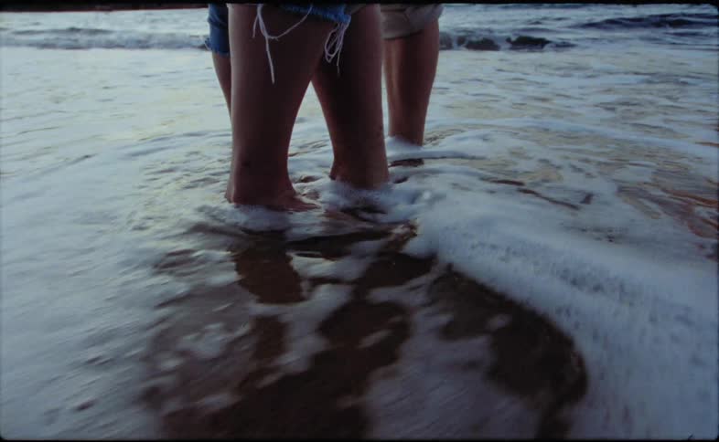 Two people are standing on the beach together