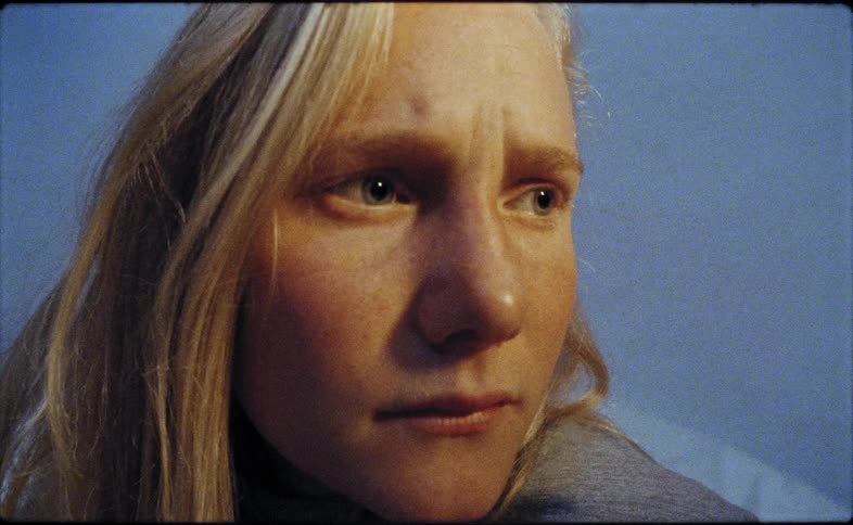 A woman looks off into the distance while sitting up in bed