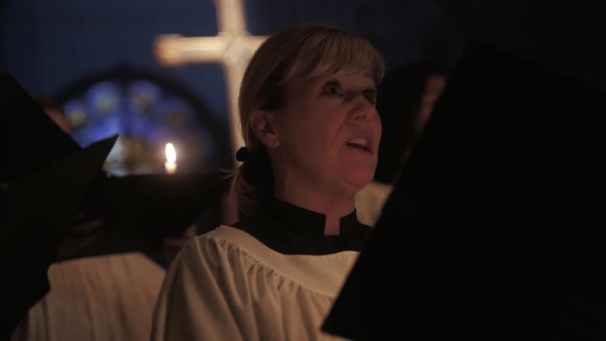 A church choir performs while holding candles