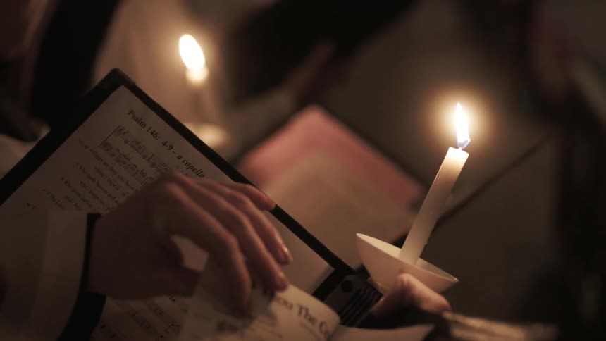 People holding candles sing