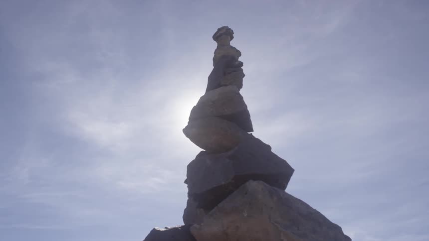 A large stack of rocks reaches into a cloudy sky