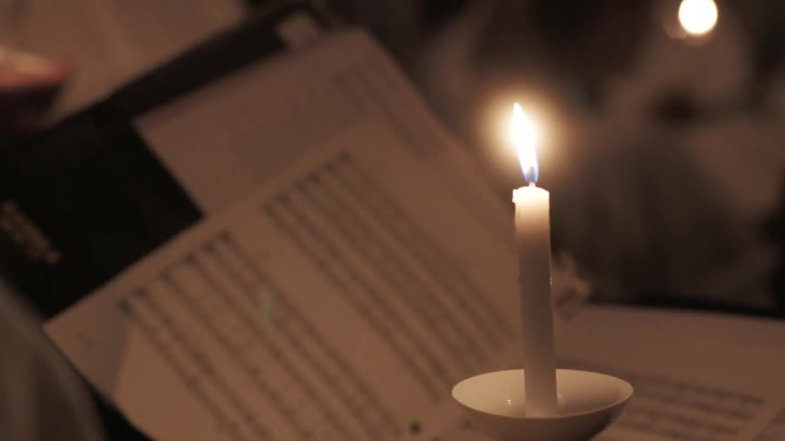 A candle lights up a song book
