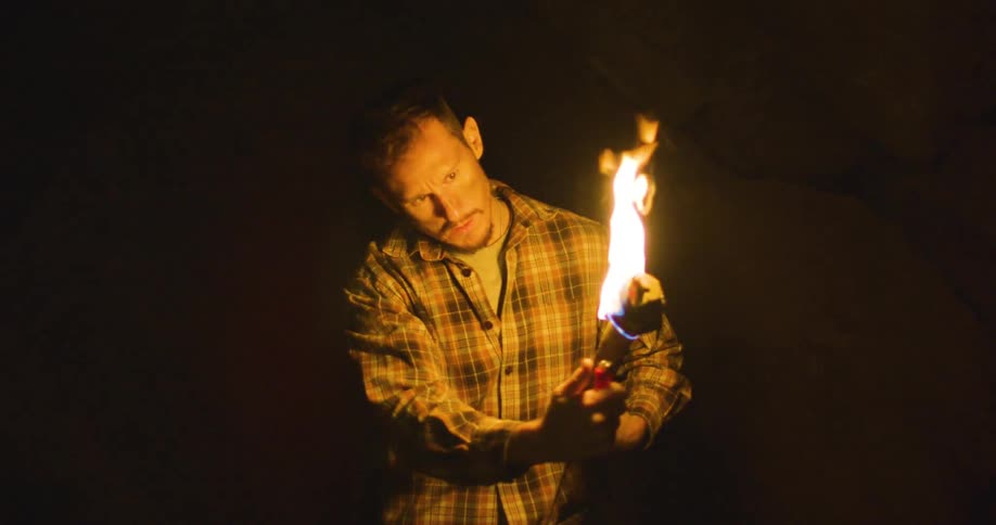 A man lighting a torch outside on a dark night