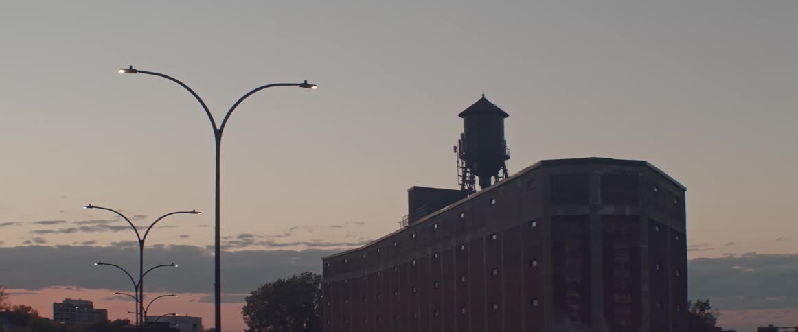 Roof top water tank sits at height with nearby streetlight against a dusk sky