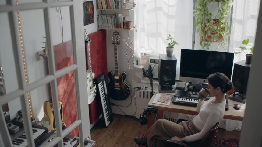 A woman is sitting at the computer and drinking coffee