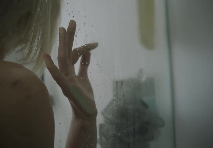 A young blonde woman is standing in the shower