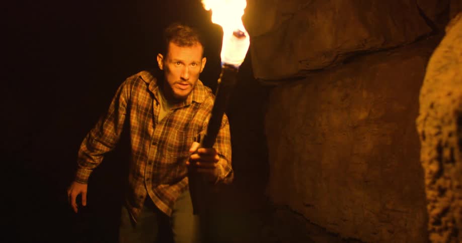 A man is walking through a cave during the night time