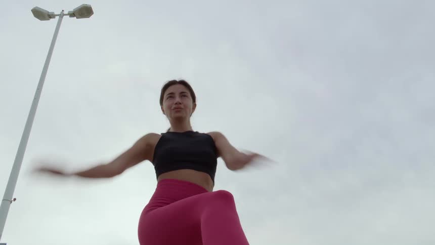 Woman stretches while working out outside under an overcast sky