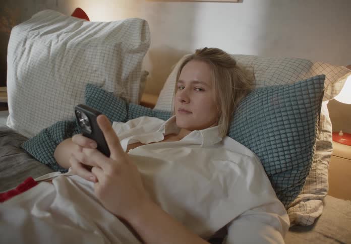 A woman is laying on a bed and texting