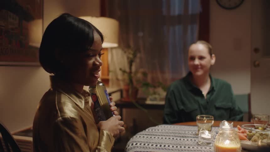 A woman is talking while holding a bottle of wine