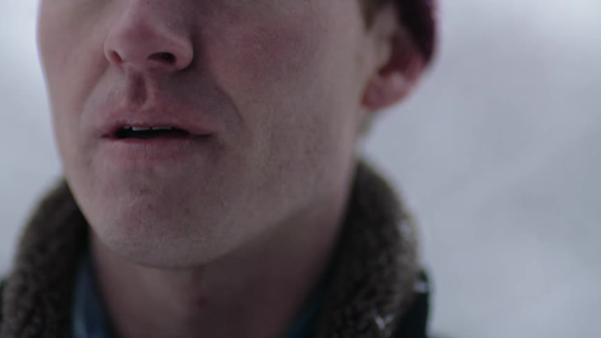 The view is of a man that is standing outside in the winter time