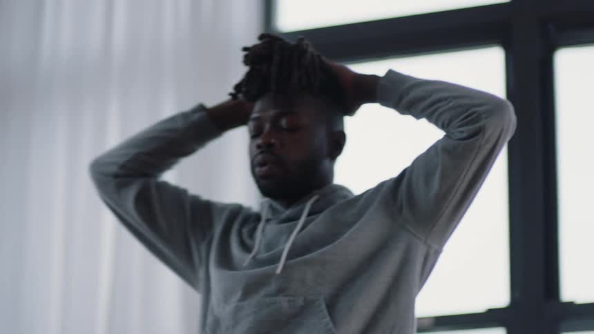 A man is pacing around his room near a window