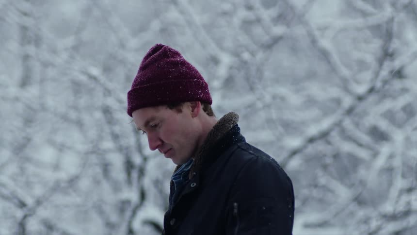 A man stands with his head bowed in a snowy forest