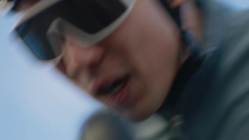 A man is wearing a cycling helmet and sun goggles as he pedals his bike