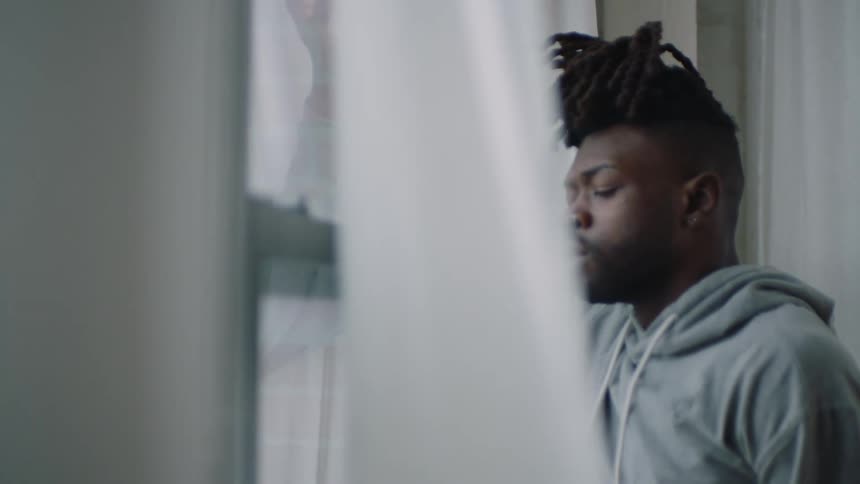 Man stands breathing deeply next to window