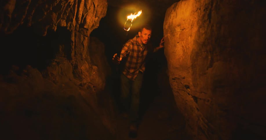 A man is walking through a cave during the night time