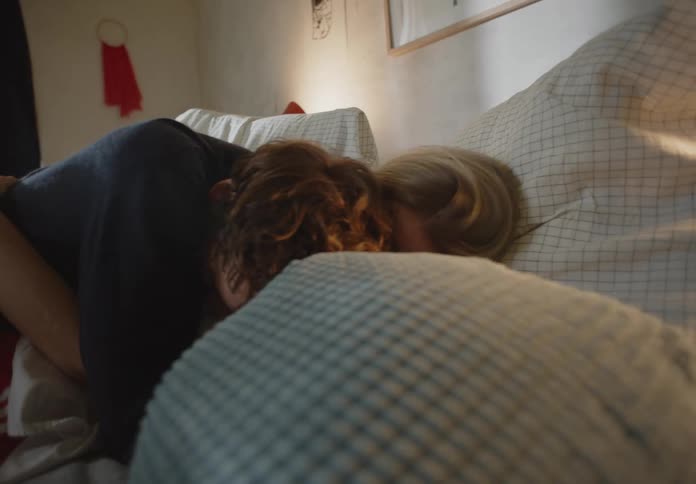 Two people laying in bed kissing