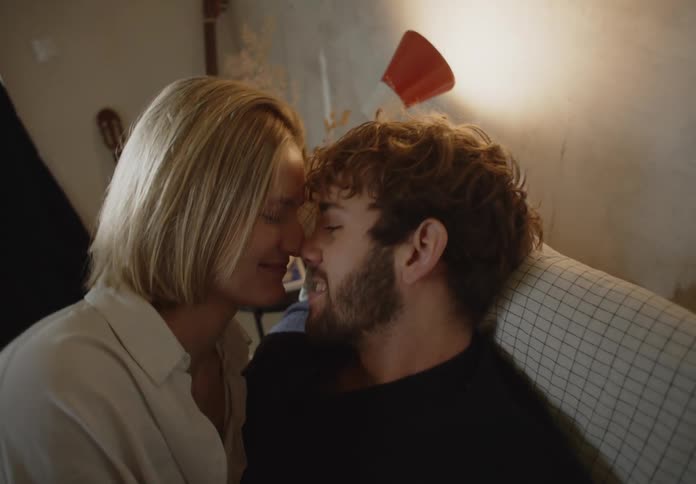 The view is of a young couple that is kissing on a couch