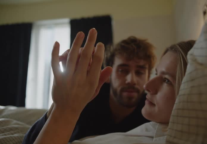 Young couple is laying in bed and is holding hands together