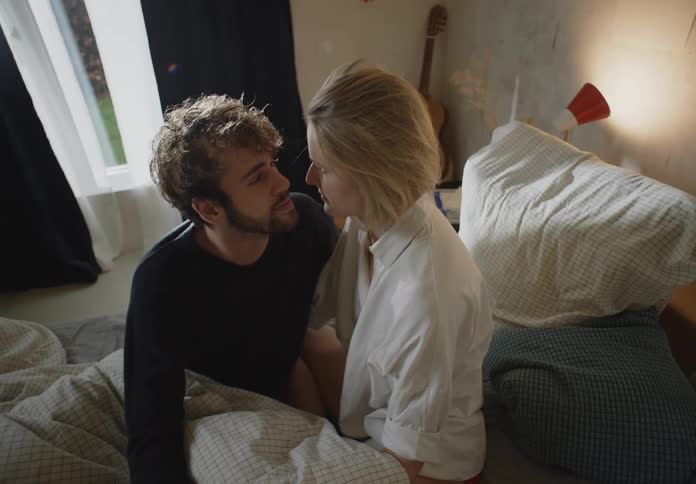 Man and woman are sitting on a bed next to each other