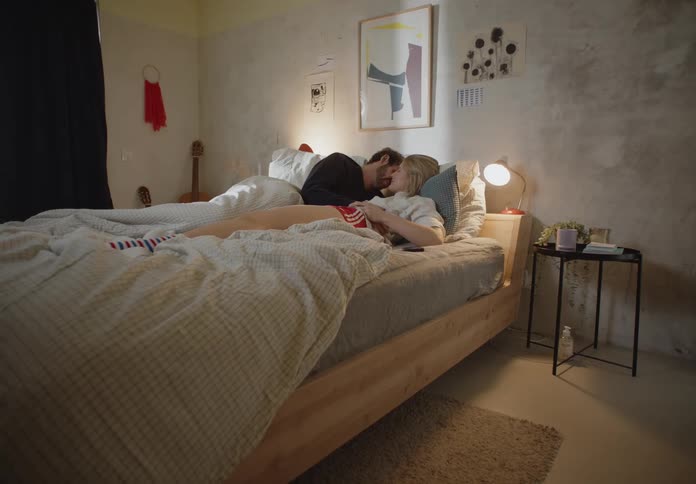 A couple embraces and kisses lying on the bed in the bedroom