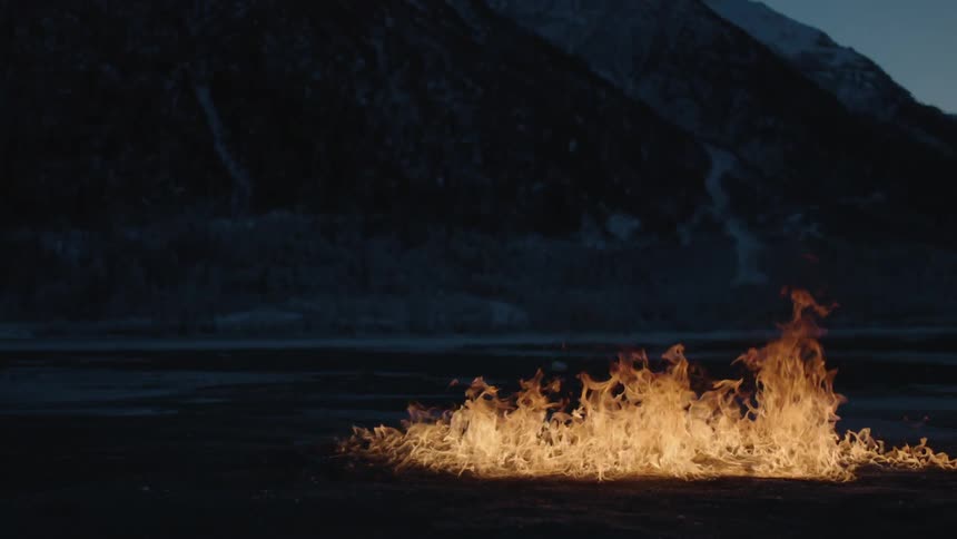 A fire ignites on the ground in the wilderness