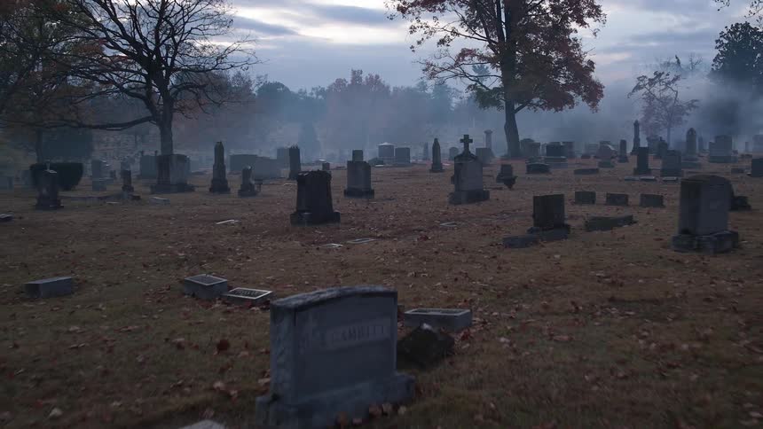 Tombstones fill a foggy cemetery