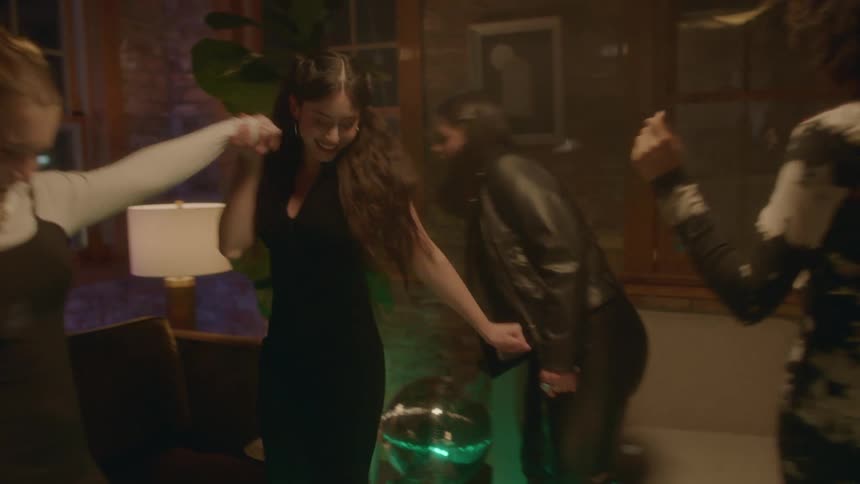 Four young women enjoying the disco lights and music dancing and laughing at a house party