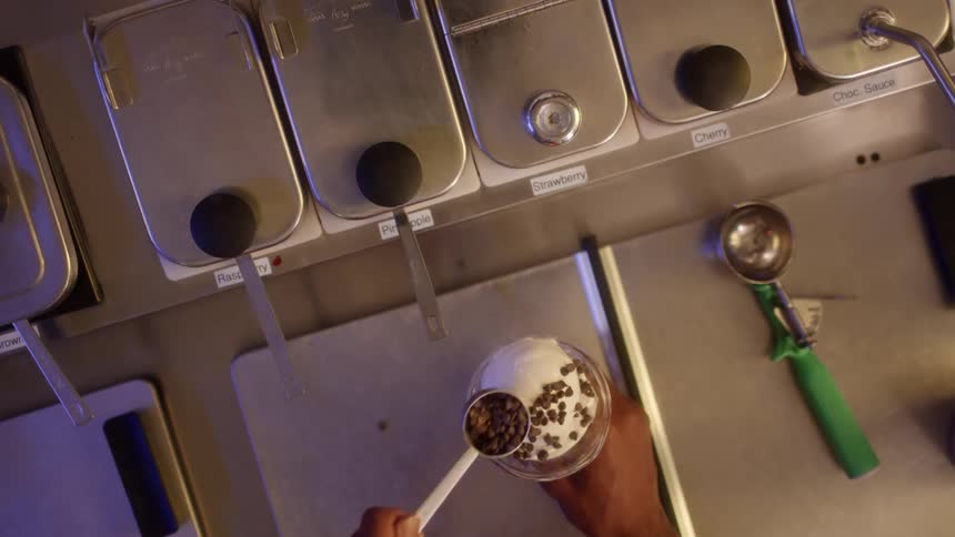 An ice cream shop employee adds toppings to a sundae
