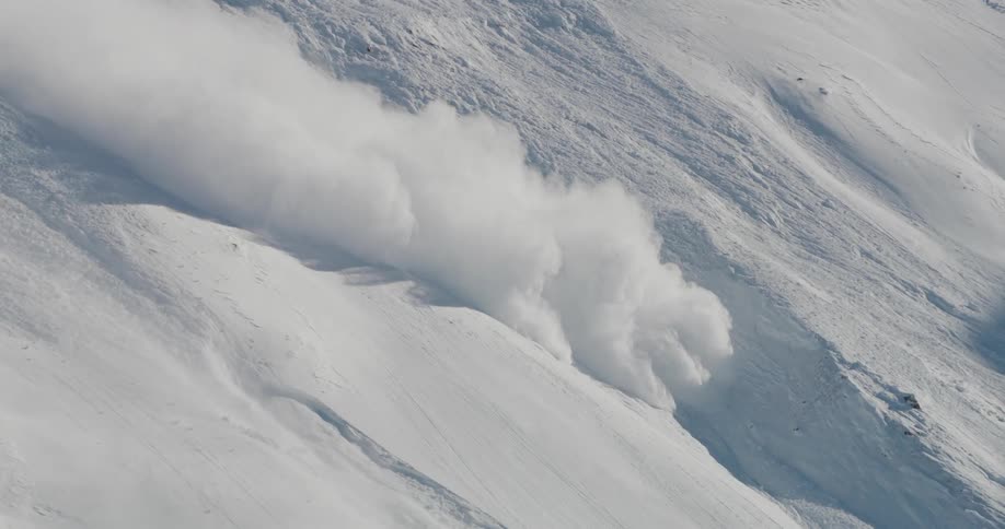 Snow falls down mountains slope during avalanche